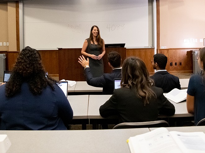 Student raising their hand during a lecture with Professor Erin Sheley