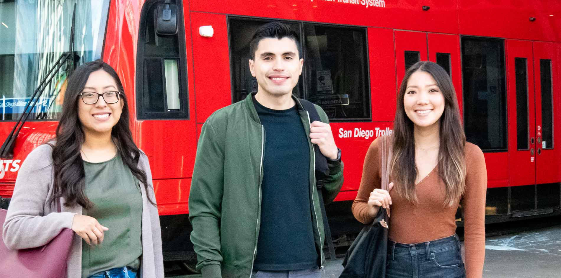 three students standing in front of San Diego Trolley stop