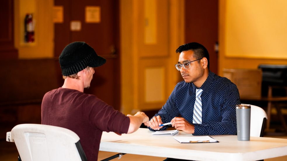 Two people talk while seated at a table