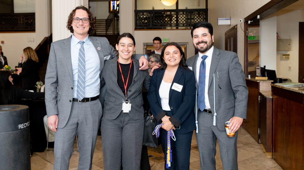 Four people pose for a photograph inside of the room hosting the ceremony celebration