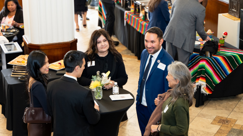 Aerial shot of ceremony celebration focusing on five people standing around a table talking