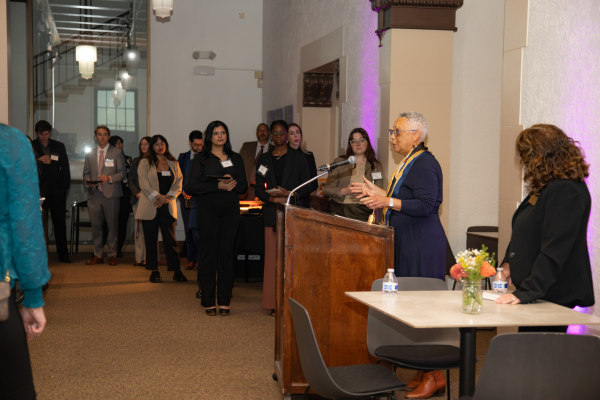 Sean Scott delivers opening remarks behind a wooden podium to a crowd of judiciary, students, staff and faculty.