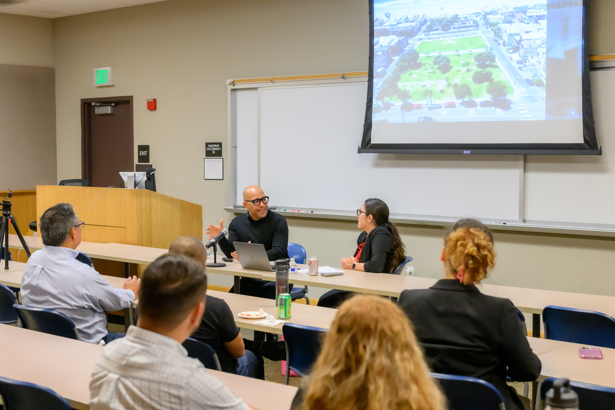 George Fatheree and Emily Behzadi Cárdenas sit at the front of a classroom audience to conduct a presentation on racial bias in property ownership.