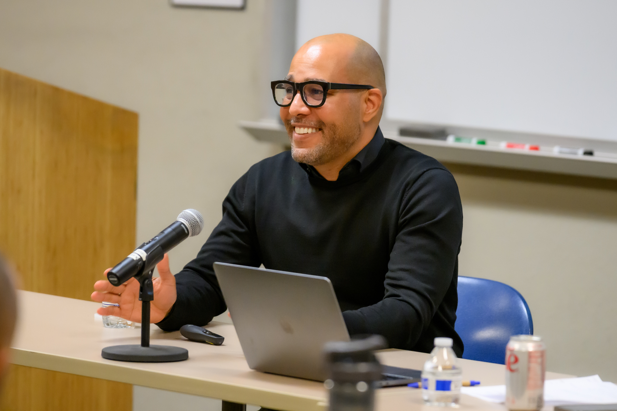 George Fatheree smiles during his talk. A microphone and laptop sit in front of him as he presents.