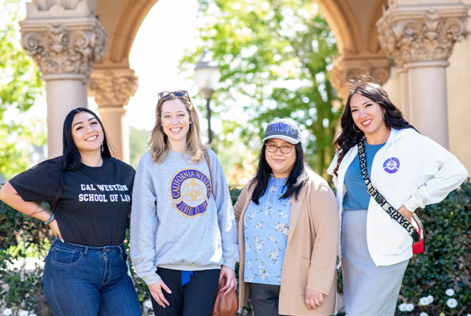 Four female students at Balboa Park smiling in California Western School of Law attire