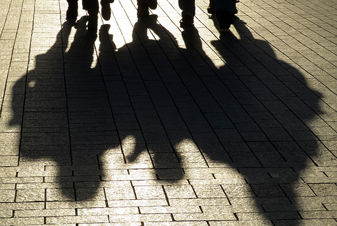 Silhouette of people walking with shadows in the street