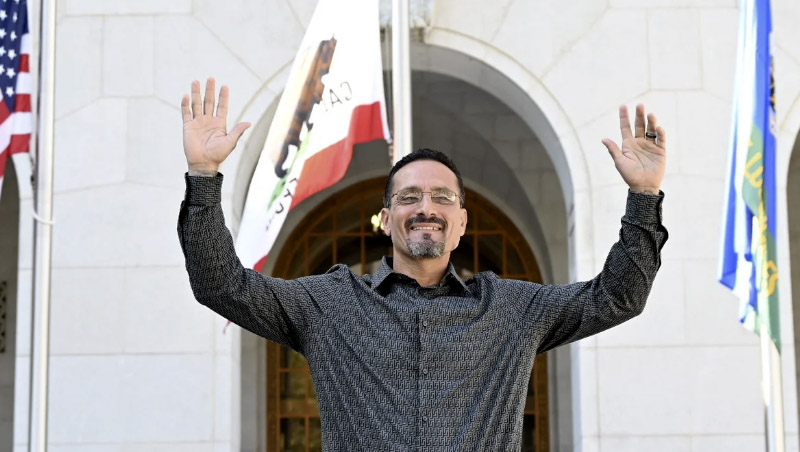 Gerardo Cabanillas stands with his arms raised in front of the Los Angeles County Courthouse. (Photo credit: Laurence Colletti of Legal Talk Network) 