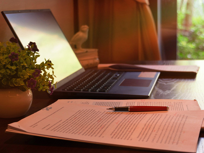 Laptop with notebook, laptop, and a pen on desk 